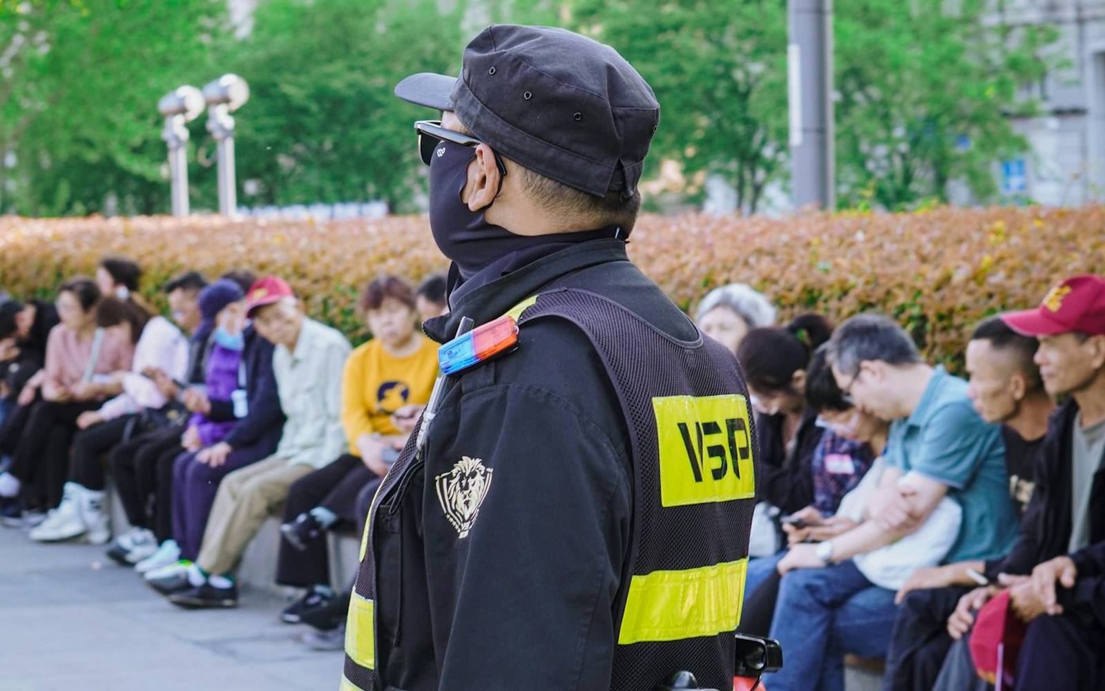 A security officer in uniform watching over a seated crowd