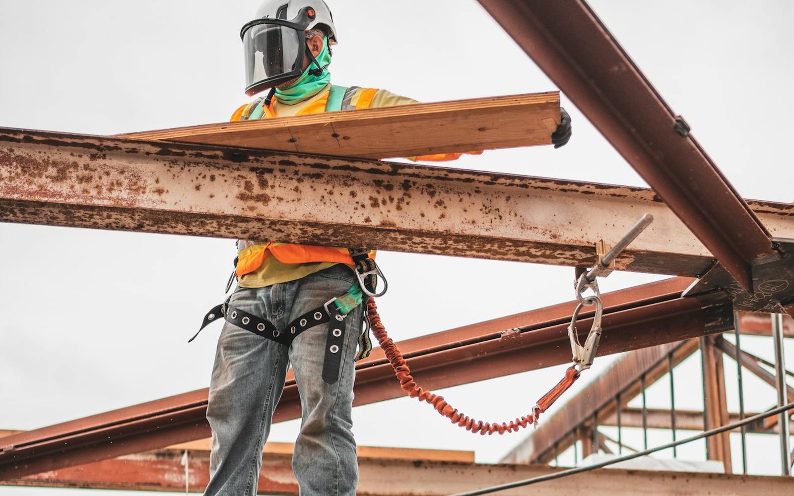 A construction worker in a safety harness on a steel frame